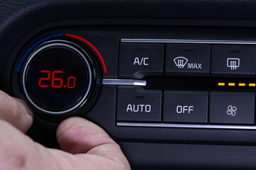 Set up air conditioner in the car. Hand turns air conditioner ring. Display indicates 26.0 degree celsius temperature inside the car. Cooling air in the car