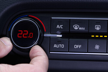 Set up air conditioner in the car. Hand turns air conditioner ring. Display indicates 22.0 degree celsius temperature inside the car. Cooling air in the car