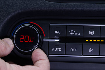 Set up air conditioner in the car. Hand turns air conditioner ring. Display indicates 20.0 degree...