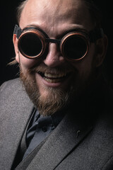 charismatic man in a classic suit and steampunk goggles on a black background stylish Portrait