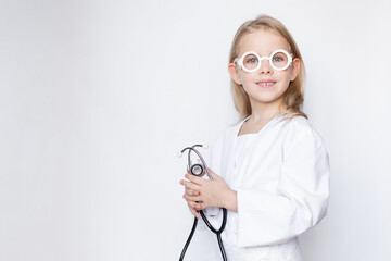 Portrait of little girl dressed up in doctor attire with toy glasses holding stethoscope, looking at camera, copy space