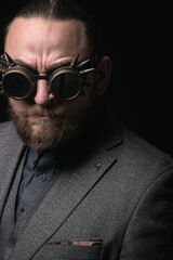 charismatic man in a classic suit and steampunk goggles on a black background stylish Portrait
