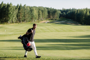 a golfer walks along a green field with a bag in which clubs. Caddy carries clubs. High quality photo