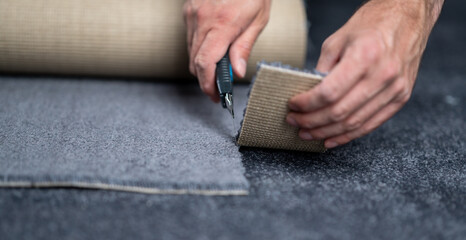 Fototapeta na wymiar Handyman cutting a new carpet with a carpet cutter...