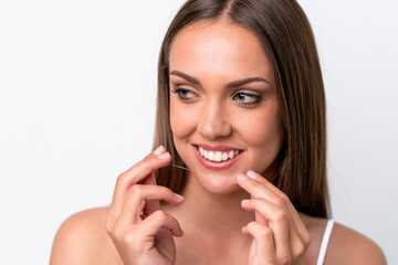 Young caucasian woman isolated on white background using dental floss with happy expression. Close...