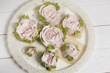 Homemade zephyr roses dry on a tray. On a white background.