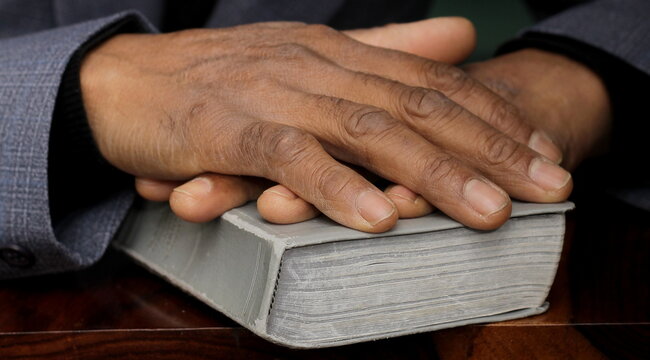 praying to God with hand on bible with background with people stock photo