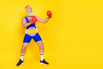 Fototapeta na wymiar Full size photo of serious strong grandfather hands boxing gloves fighting empty space isolated on yellow color background