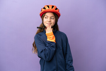 Little caucasian girl isolated on purple background looking up while smiling