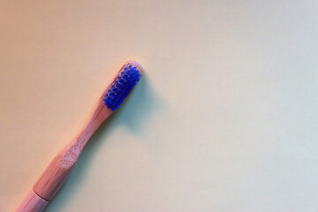 Sustainable wooden toothbrush on pastel yellow background. Top view.