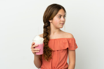 Little caucasian girl with strawberry milkshake isolated on white background looking to the side