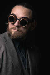 Fototapeta premium charismatic man in a classic suit and steampunk goggles on a black background stylish Portrait