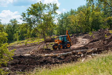yellow tractor is working on cleaning the territory, preparing the park