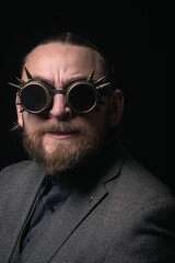 Obraz premium charismatic man in a classic suit and steampunk goggles on a black background stylish Portrait