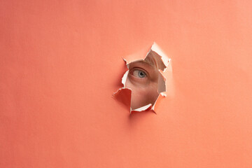 a man looks through a cut hole in the paper. observer through paper
