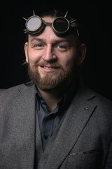 Obraz premium charismatic man in a classic suit and steampunk goggles on a black background stylish Portrait