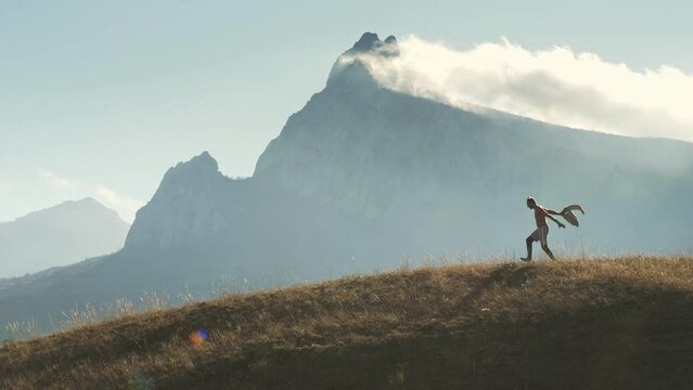 The idea of joy and reinvention. A joyful man gallops and burps with happiness at the top of the hill. The backdrop is from the fog of the mountains.