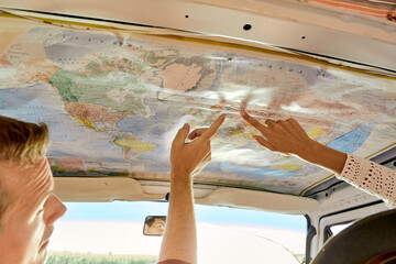 Cropped Couple enjoying travel and wanderlust lifestyle reading map and planning the trip while sitting inside an old vintage hand made customized van, view from back. travel, trip, adventure