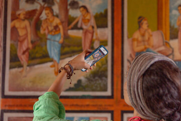 Young tourist woman taking photo with her phone in the Buddhist temple at Sri Lanka.