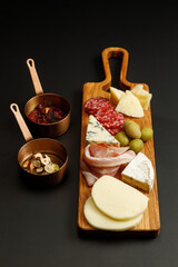 Assortment of different types of cheese and sausages, served with sauces. Cheese board.