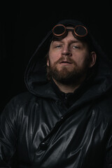 Obraz premium A man in a hood, wearing vintage steampunk goggles looking at the camera close-up
