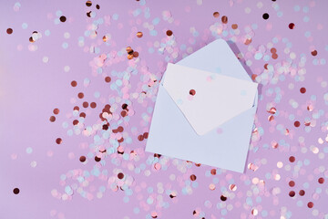 Blue envelope with blank white paper with pastel colorful confetti on lilac background. Concept with  copy space. Birthday or holiday invitation