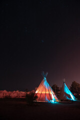 Two teepees illuminated at night under a sky of stars in Marfa, Texas with copy space © TomWindeknecht
