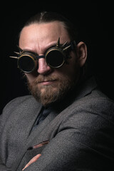 charismatic man in a classic suit and steampunk goggles on a black background stylish Portrait