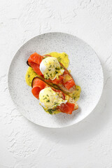 Toasts with smoked salmon fish and poached eggs on top isolated on white concrete background
