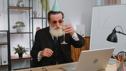 Senior old business man wears sunglasses, festive cap, drinking champagne at workplace dancing...