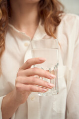 Caucasian woman is consuming mineral water indoors