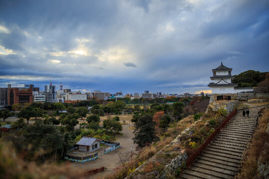 Dramatic sky over stairs to Japanese castle tower and city skyline