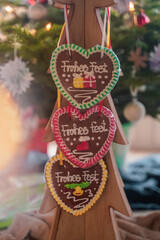 Colorful Christmas gingerbreads in the shape of heart hangs on wooden tree close-up. Behind Christmas decor. Christmas food. Christmas atmosphere. Selective focus