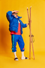 Active holidays, vacation. Portrait of handsome man in blue winter jacket posing with skis over...