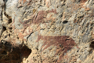 Ancient stone walls, brown and very old, with painted patterns on the surface.