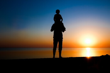 A Happy parent with child by the sea play on nature silhouette travel