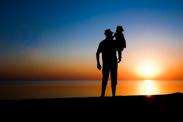 A Happy parent with child by the sea play on nature silhouette travel