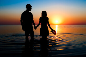 A Happy couple by the sea at sunset on travel silhouette in nature