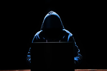 A Hacker with laptop sits at a table and abstract binary code. Business life threat virtual...