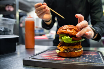 chef hand preparing a gourmet burger on restaurant kitchen step by step
