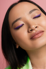 Obraz premium close up view of young asian woman with perfect makeup with blue eyeliner isolated on pink.