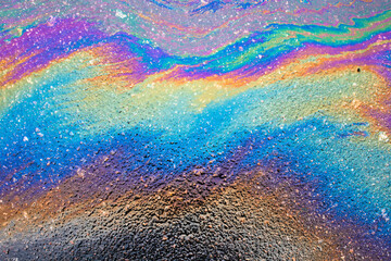 Multi colored oil spill on asphalt road, abstract background