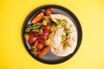 Hearty breakfast in a black plate on an orange background. View from above. Food photography.