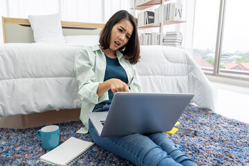 Naklejka premium Asian woman working at bedside in bedroom at home with her tablet