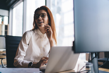 Cheerful businesswoman smiling while working on netbook