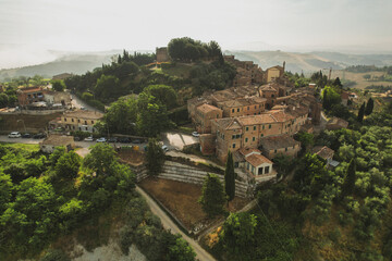 Fototapeta premium Small village of Chiusure on top of the hill surrounded by Karst cliffs landscape photographed with a drone. Toscana, Tuscany, Asciano, province of Siena in Italy with a little mud road 06.16.2021