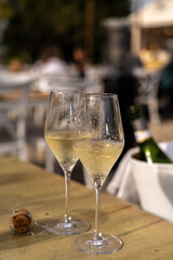 Two glasses of cold sparkling wine on a table in outdoor restaurant. Celebration during the sunny day.