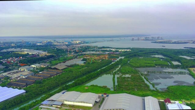 Flying over the river of Lamong East Java with the view of shipping containers by the river banks. Aerial shot.