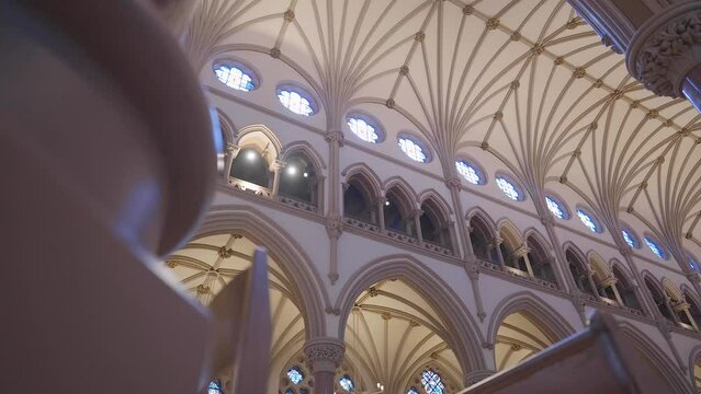 Panning through phews inside of a catholic church to reveal light