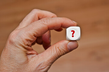 hand holding a die with a question mark 